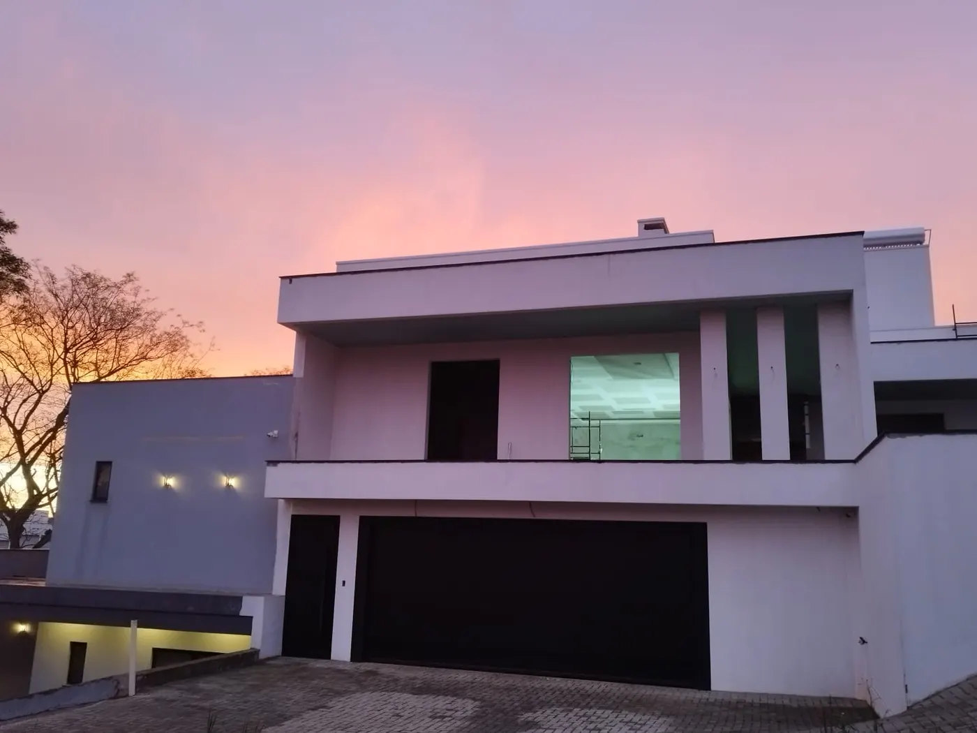 Casa moderna em fim de obra ao entardecer, com forro de gesso já instalado na sala do andar de cima